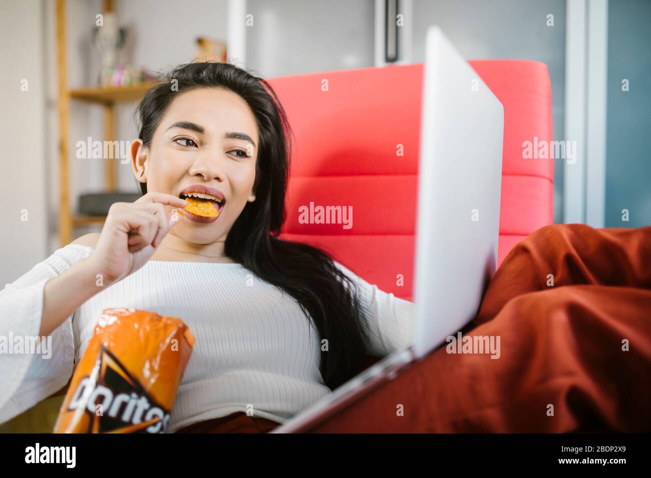 Schöne asiatische Frau essen Doritos. Stockfoto