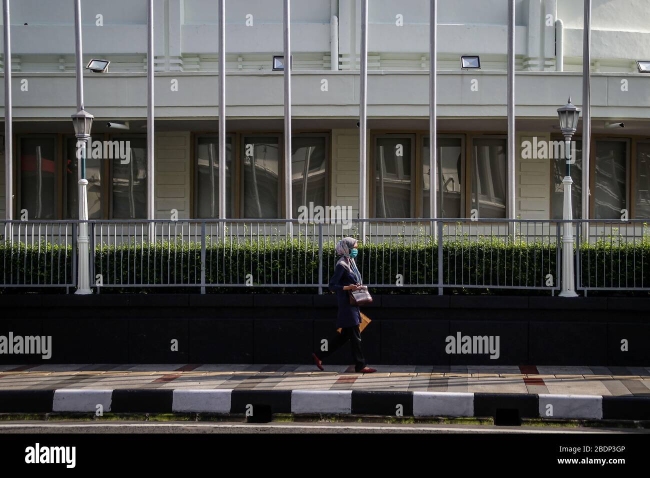 Eine Frau, die eine Schutzmaske trägt, spaziert vor einem Gebäude der Asia Africa Conference inmitten von Bedrohungen durch Coronavirus. Das indonesische Gesundheitsministerium bestätigte 3.293 Fälle von COVID-19, 252 Menschen, die sich erholen und 280 Todesfälle. Stockfoto