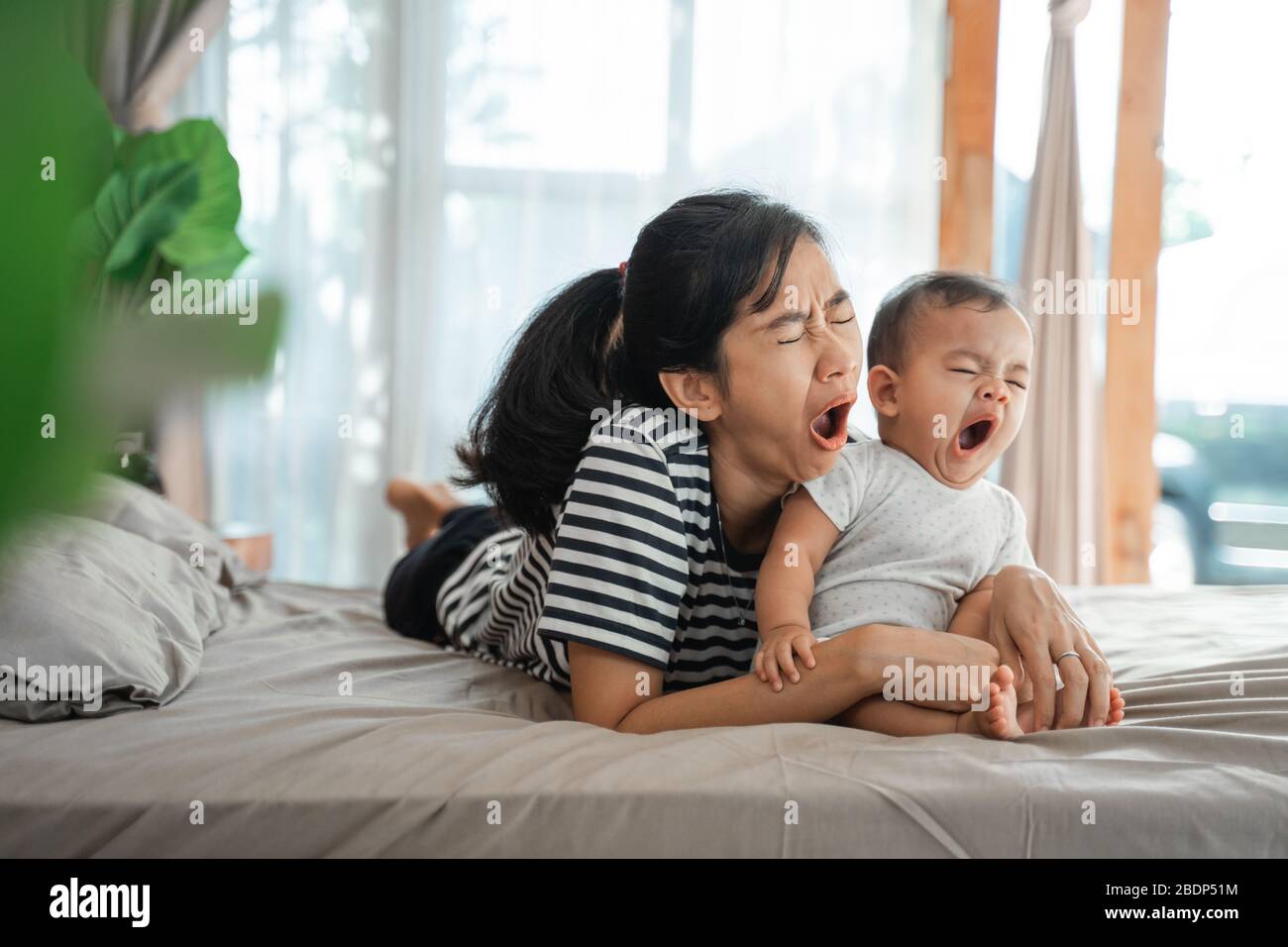 Mutter und Kind gähnen beim Auflegen auf das Bett zusammen Stockfoto