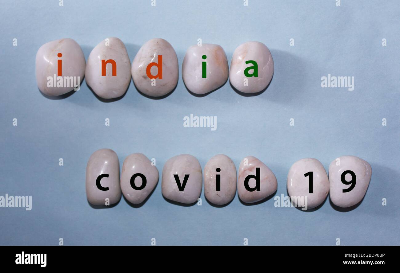 Konzept Coronavirus. indien covid 19 als Text mit Buchstaben auf weißen königlichen Saphir-Felsen Kieselsteinen, Schablone vor blauem Hintergrund Stockfoto