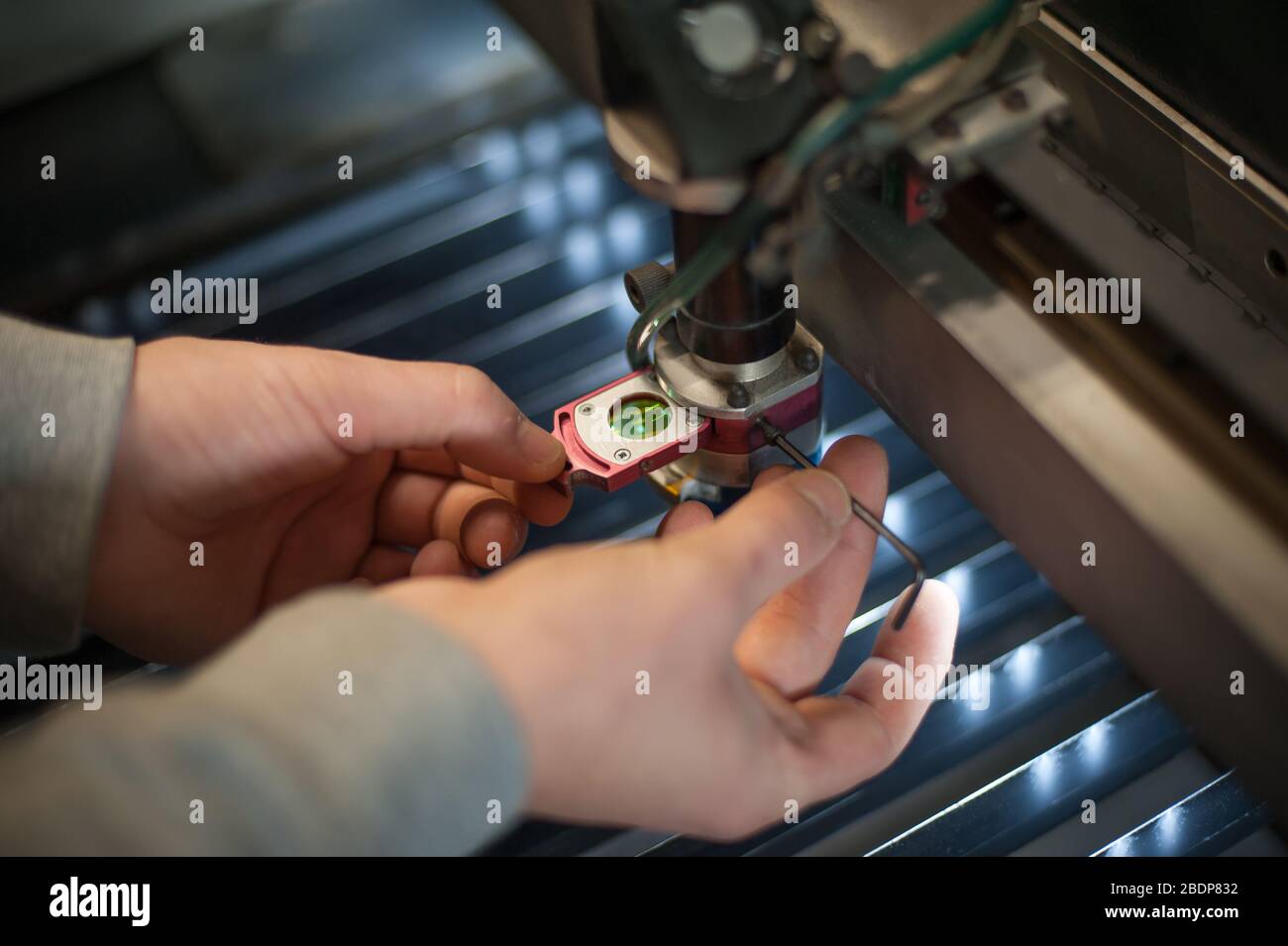 Elektroingenieur repariert einen Laserschneidkopf an einer großen CNC-Computernumeriermaschine für Druck- und Schneidmaschinen Stockfoto