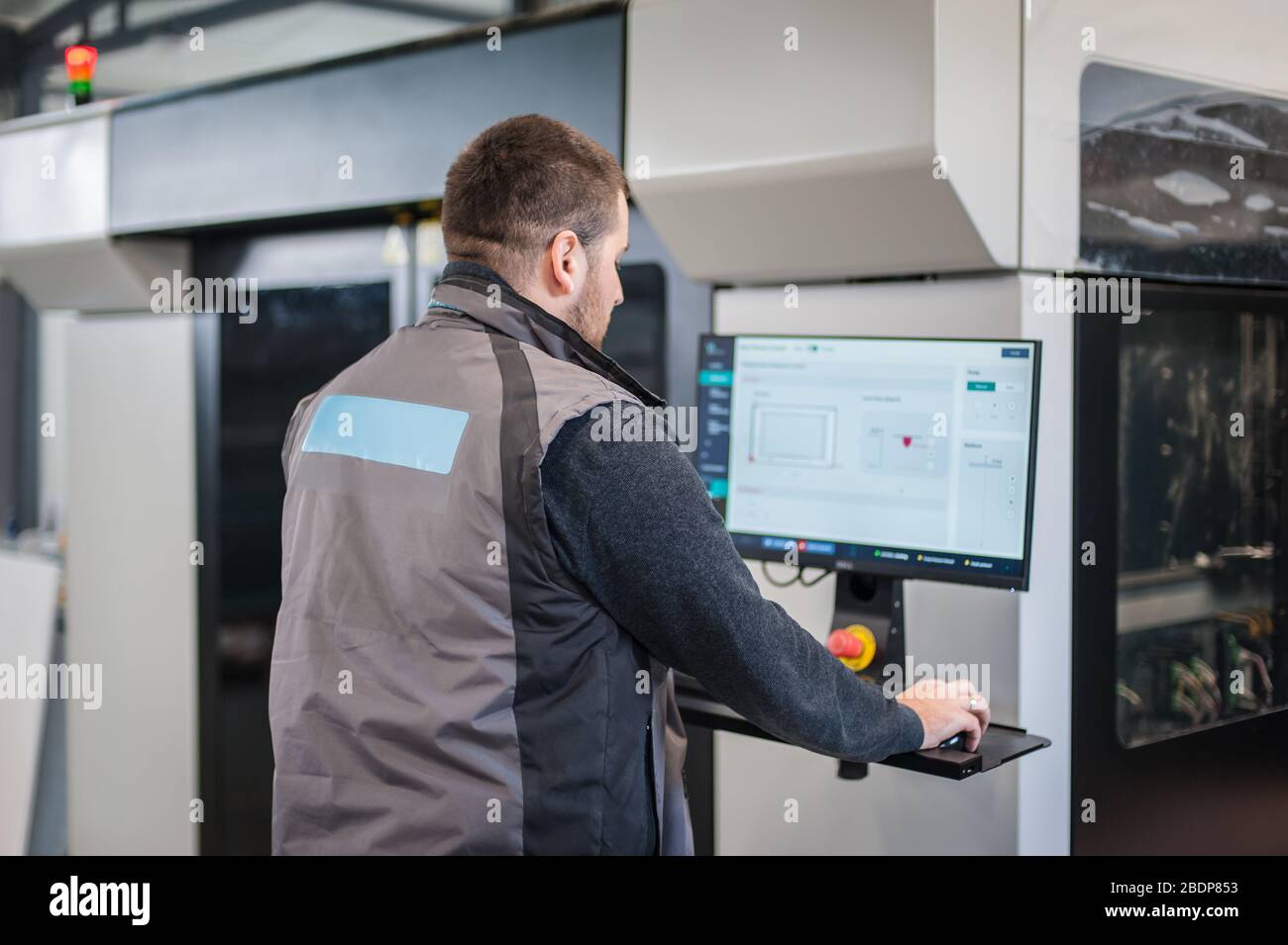 Der Druckereifachmann arbeitet an einem großen modernen 3D-Druckergerät mit Computersteuerung Stockfoto