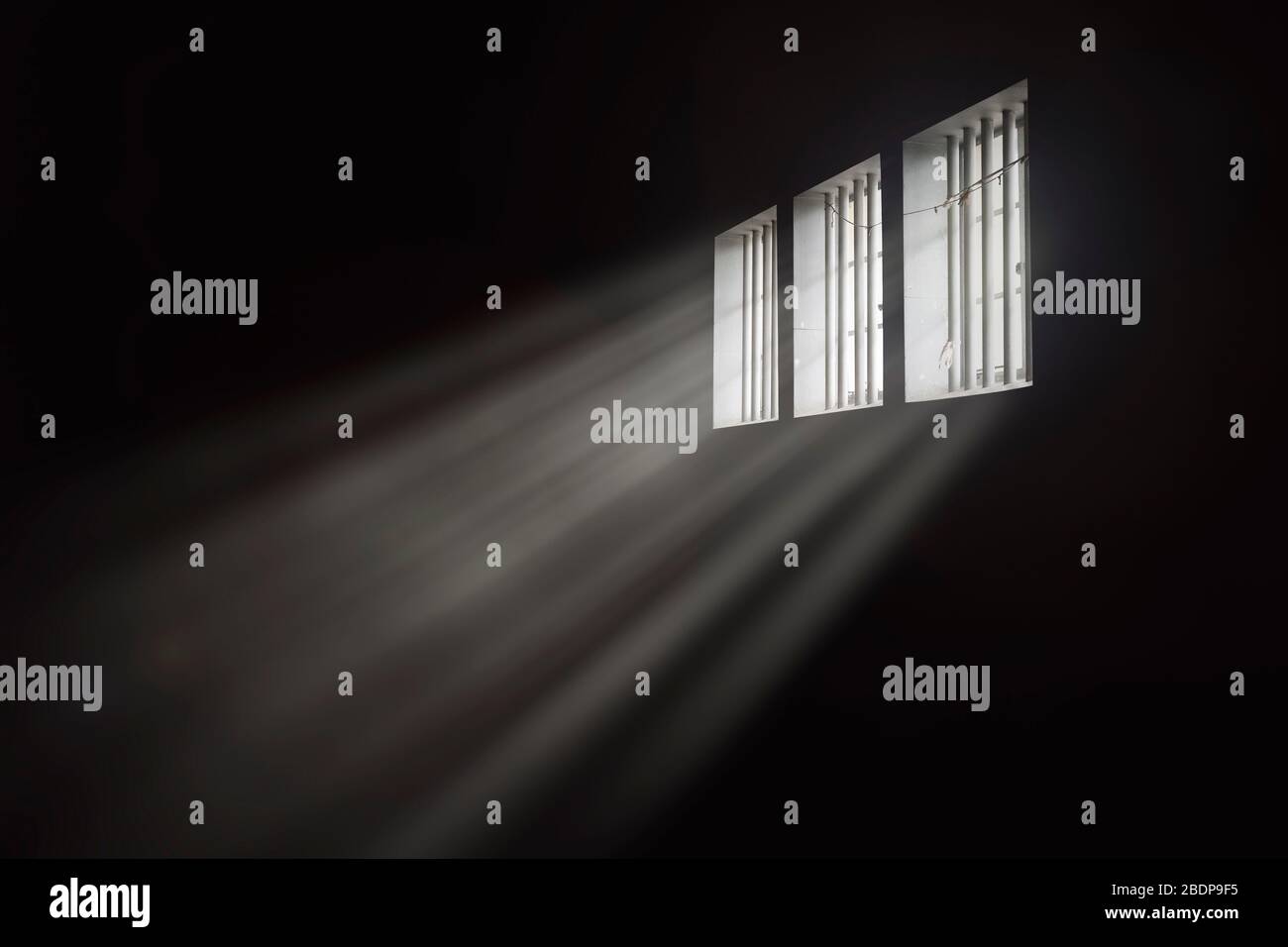 Lichtstrahlen durch ein gesperrtes Fenster der Gefängniszelle Stockfoto
