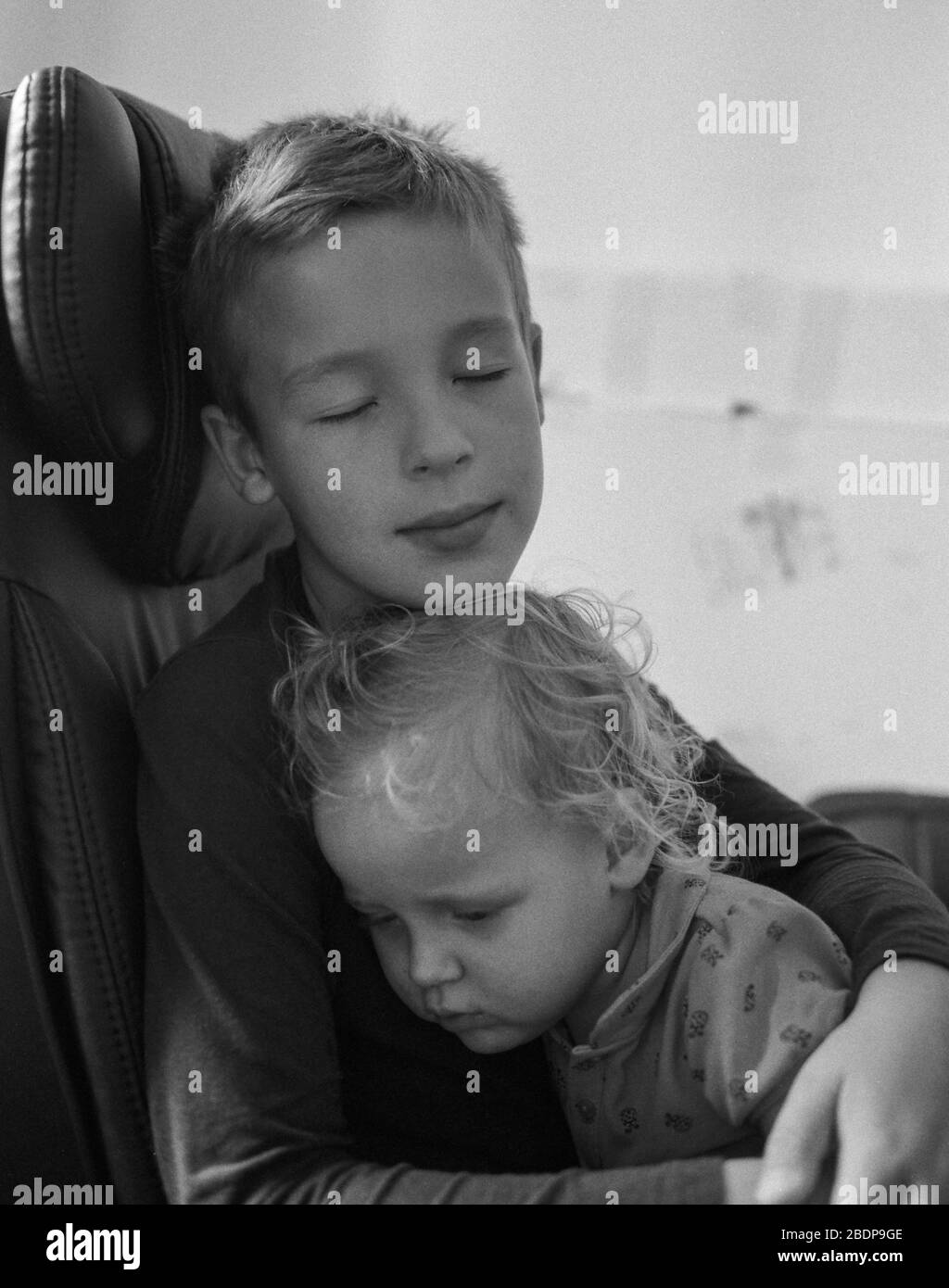 Liebevoller Bruder tröstend Baby Schwester in Umarmungen Stockfoto