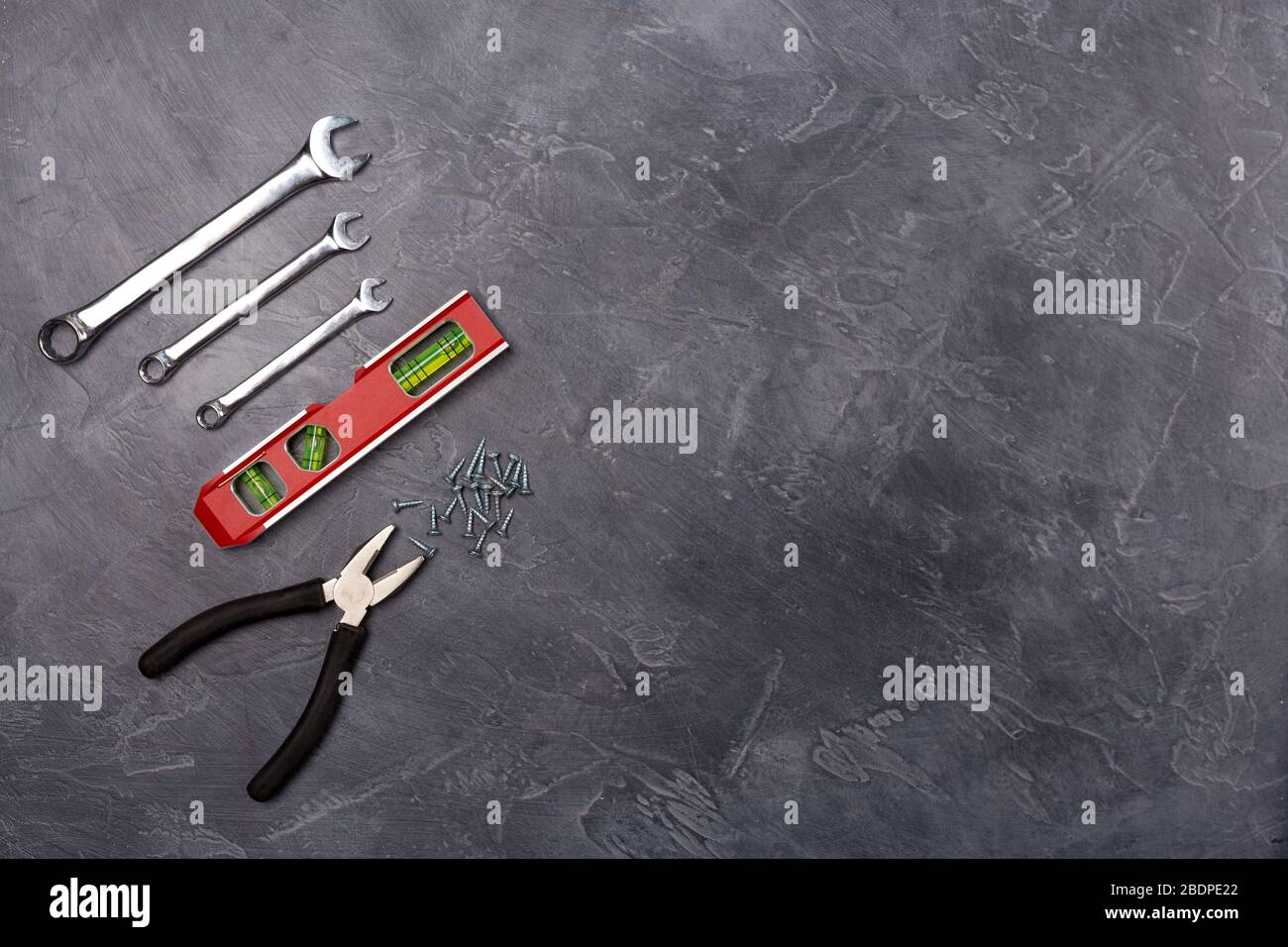 Verschiedene Handwerkzeuge für Konstruktion, Reparatur- Zange, Niveauwerkzeug, Schraubenschlüssel auf grauem Hintergrund. Draufsicht, Streuung. Freier Speicherplatz. Kopierbereich. Stockfoto