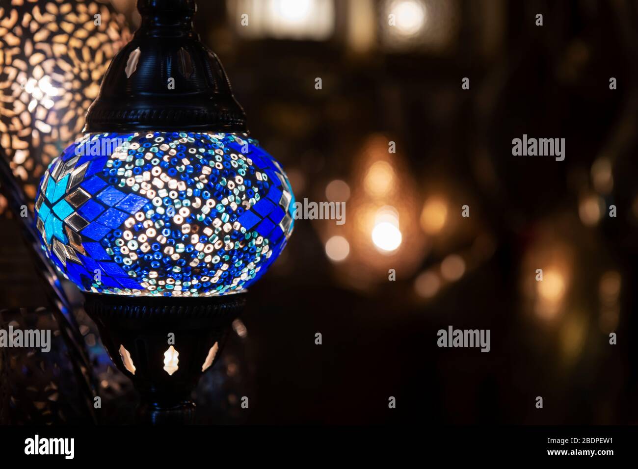 Bunte blaue marokkanische Lampe mit blauem Mosaikdesign aus Glas. Orientalischer Stil. Vor Bokeh-Hintergrund. Stockfoto