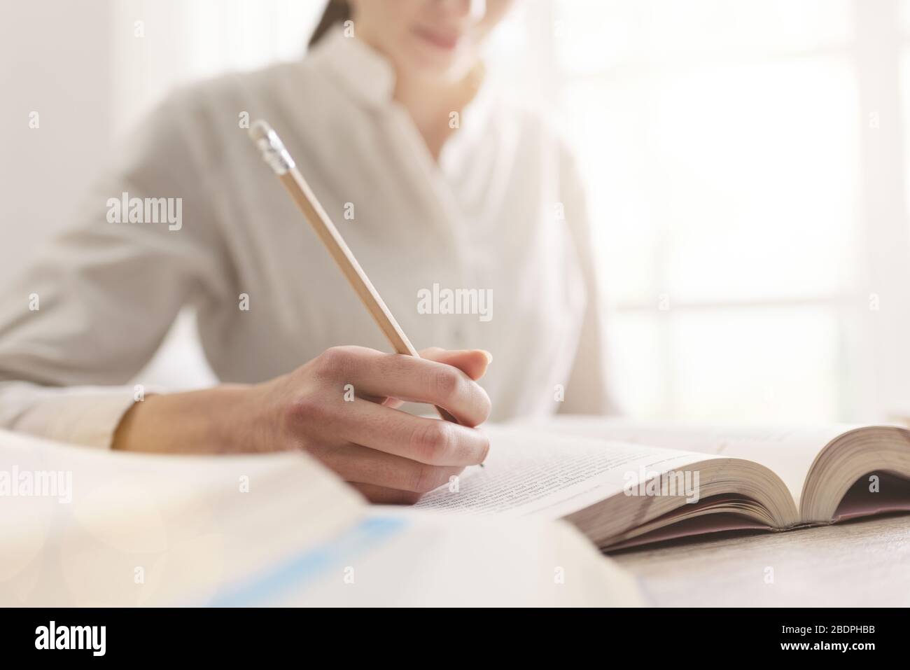 Student des College, schreibt Notizen zu einem Buch, macht Nahaufnahme Stockfoto