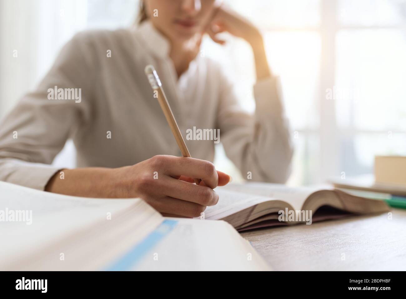 Student des College, schreibt Notizen zu einem Buch, macht Nahaufnahme Stockfoto