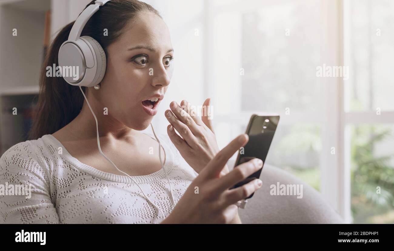 Schockierte Frau, die Musik hört und eine Fehlermeldung auf ihrem Smartphone empfängt Stockfoto