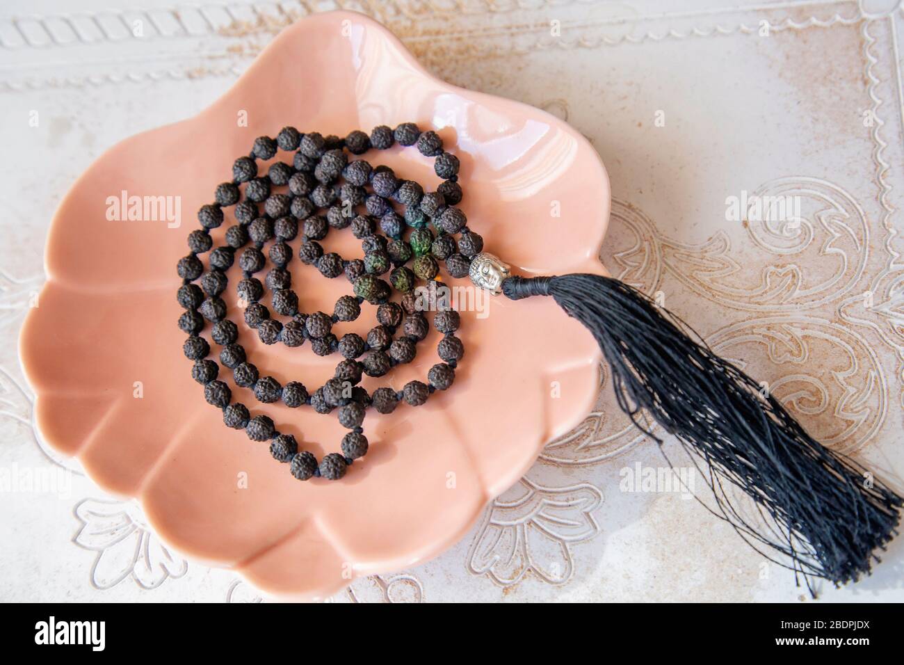 Indische Rudraksha Samen Perlen 108 mala Halskette mit Buddha Anhänger Quaste auf dekorativen Rücklauf Stockfoto