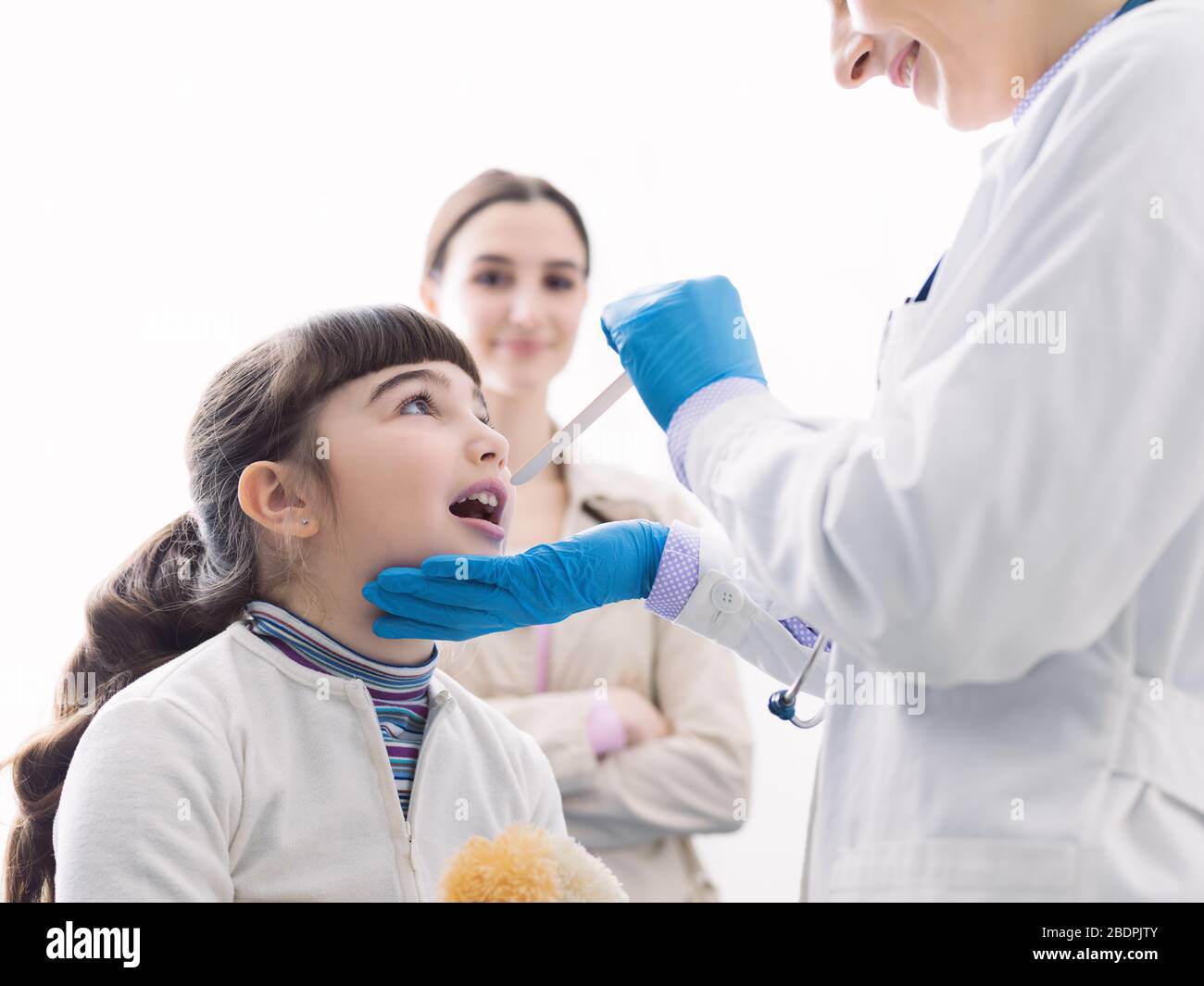Professionelle Ärztin überprüft die Kehle eines Mädchens, sie öffnet ihren Mund Stockfoto