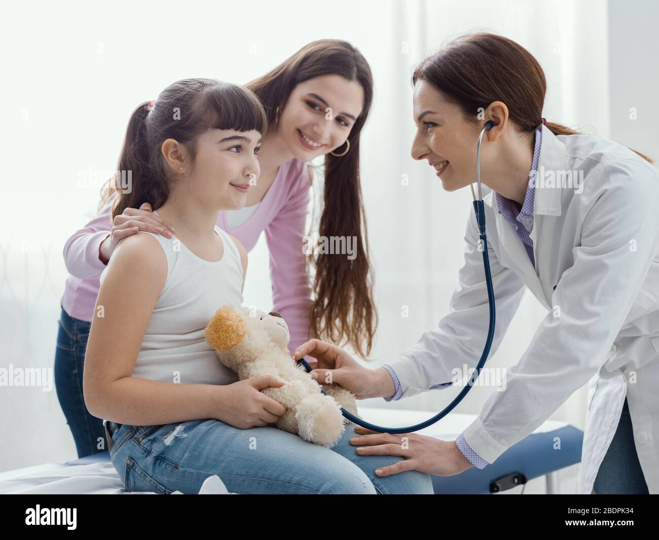 Doktor, der ein süßes Mädchen besucht und mit ihr spielt, überprüft sie den Herzschlag des Teddybären mit einem Stethoskop, Kindern und Gesundheitskonzept Stockfoto