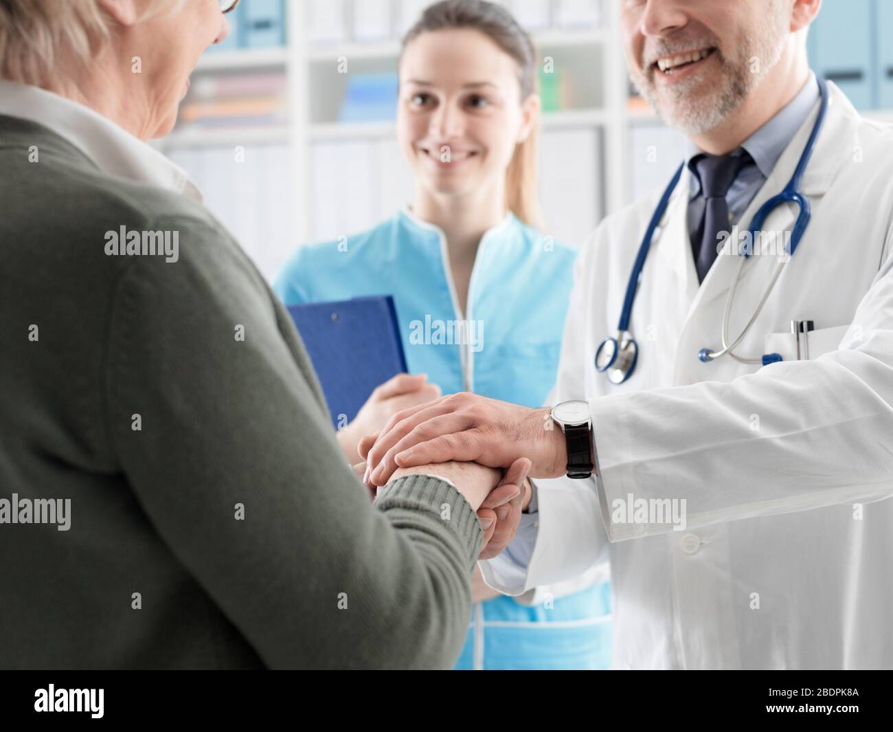 Professioneller Arzt hilft und unterstützt einen leitenden Patienten, er hält sich die Hände, das Konzept für das Gesundheitswesen und die Geriatrie Stockfoto