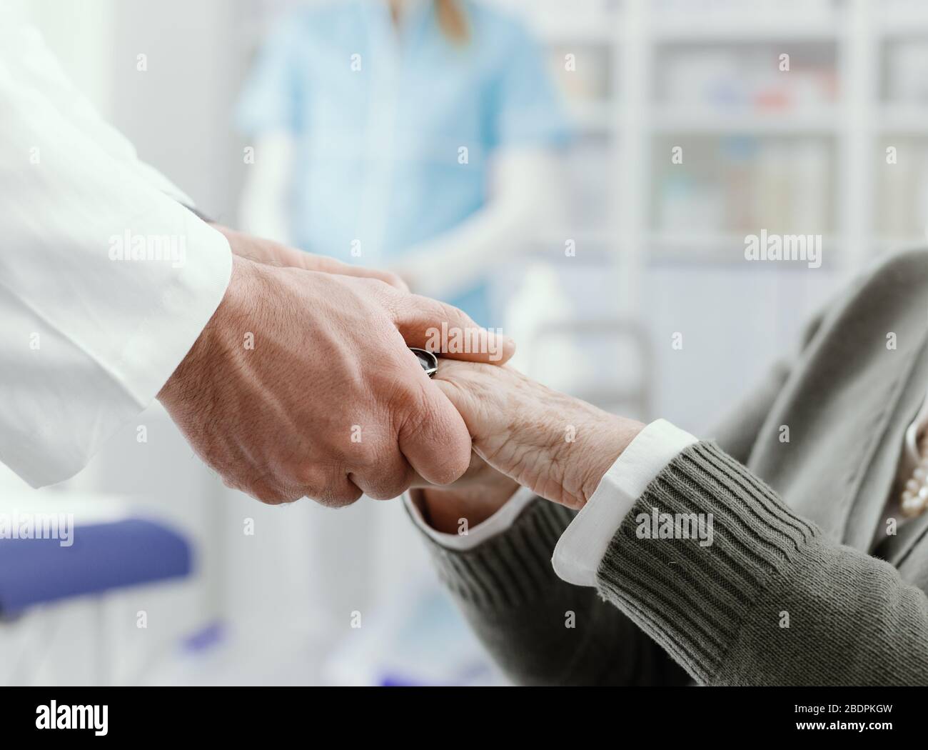 Professioneller Arzt hilft und unterstützt einen leitenden Patienten, er hält sich die Hände, das Konzept für das Gesundheitswesen und die Geriatrie Stockfoto