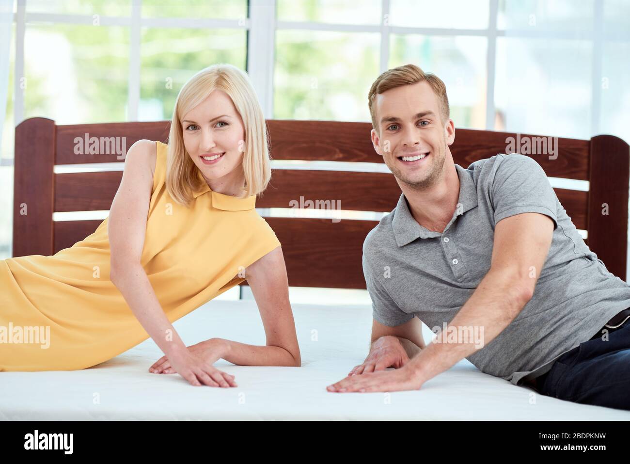 Porträt des schönen und glücklichen jungen Paar testen eine neue ergonomische Matratze für ihr Bett und lächeln vor der Kamera. Gesundheitswesen. Familienkonzept. Hoffnung. Schlafzimmer Stockfoto