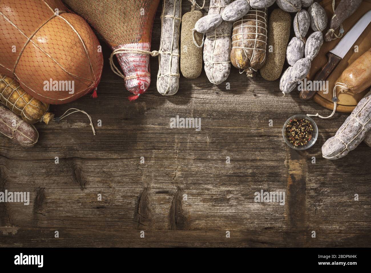 Traditionelle Salami und gehärtetes Fleisch auf einem rustikalen Holztisch: Würstchen, Schinken, Sterbadellen und Gewürze Stockfoto