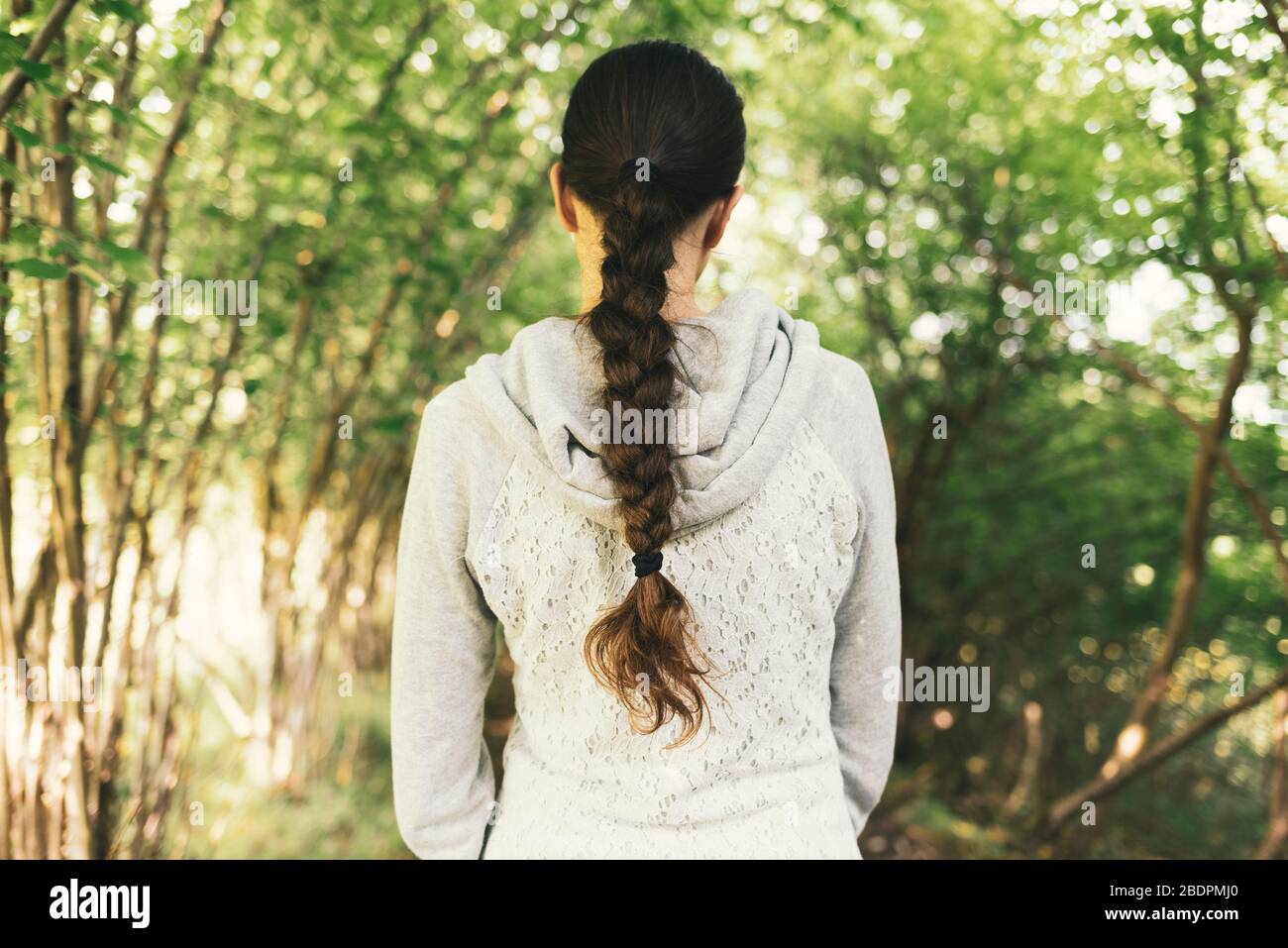 Junge Frau, die in der Natur spazieren geht und einen entspannenden Blick auf den Rücken hat, hat eine schöne frisierte Frisur, einen Blick auf den Rücken Stockfoto