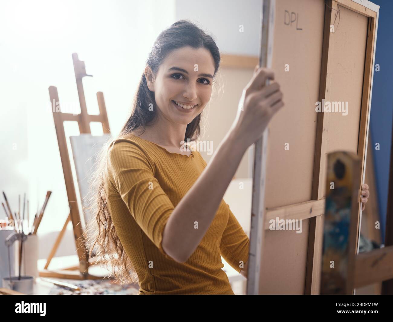 Junge Künstlerin legt eine Leinwand auf die Staffelei und überprüft ihr Gemälde-, Kunst- und Kreativitätskonzept Stockfoto
