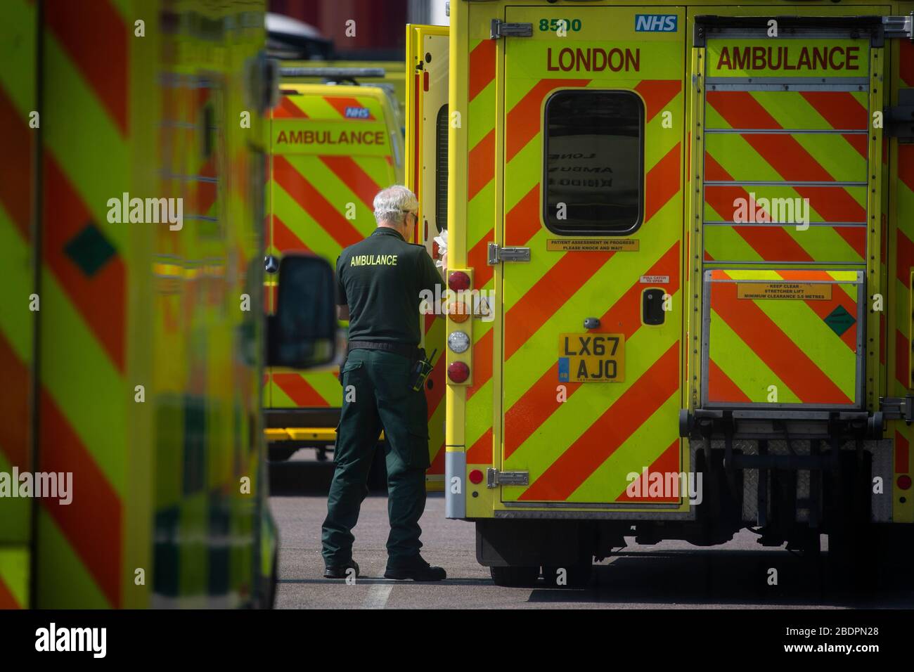 Ein NHS-Mitarbeiter reinigt einen Krankenwagen außerhalb des NHS Nightingale Hospital im Excel Center in London, einem temporären Krankenhaus mit 4000 Betten, das für die Behandlung von Covid-19-Patienten eingerichtet wurde. Stockfoto