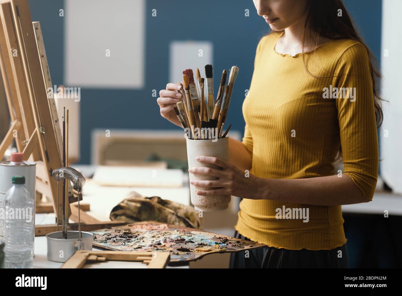 Junge Frau malt im Atelier und wählt die richtige Bürste für ihr Kunstwerk Stockfoto