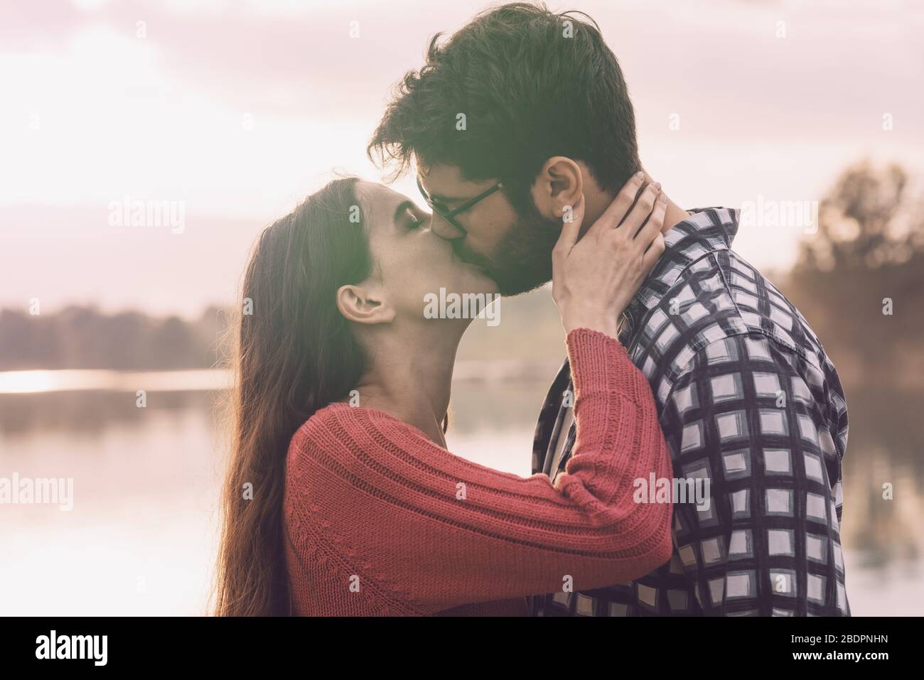 Junges romantisches Paar küsst draußen am See, Jugend- und Beziehungskonzept Stockfoto