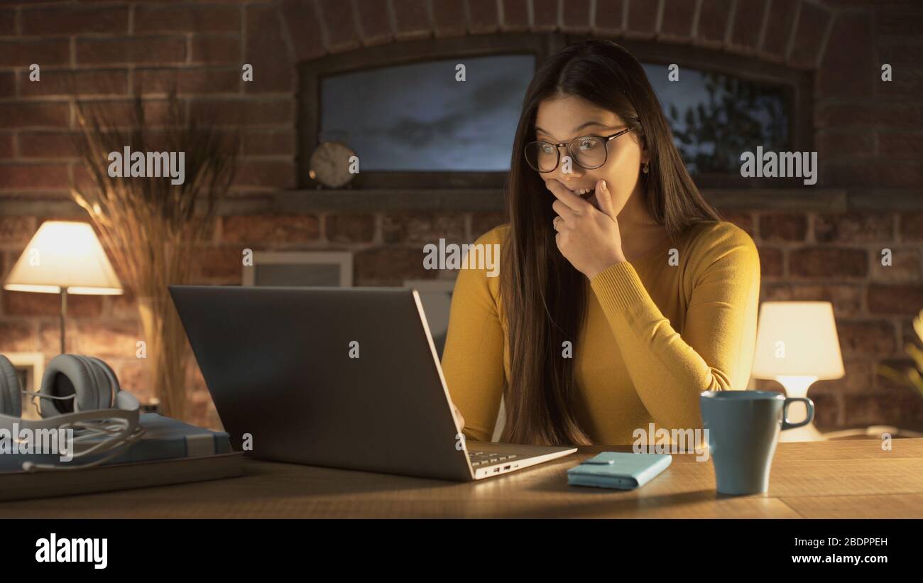Schockierte überraschte Frau, die sich zuhause mit ihrem Laptop verbindet Stockfoto