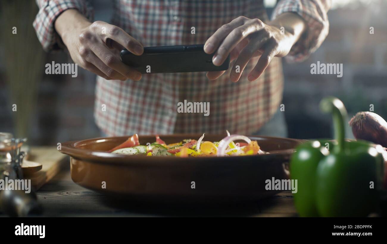 Frau bereitet eine gesunde Mahlzeit mit frischem Gemüse vor und macht mit ihrem Smartphone ein Foto Stockfoto
