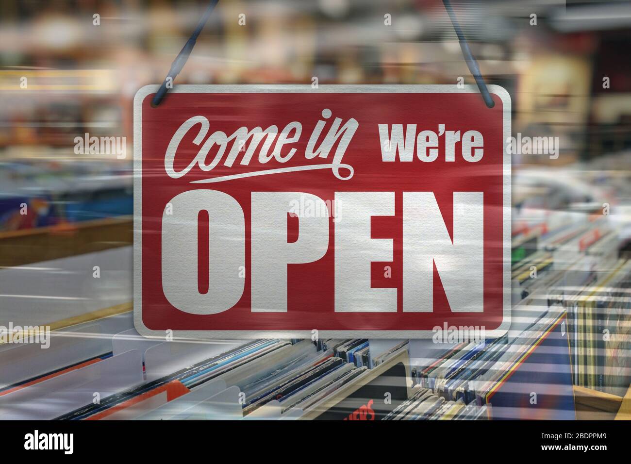 Ein Geschäftszeichen, das in einem Fenster eines Musik-/Plattengeschäfts „Come in We're Open“ steht. Stockfoto