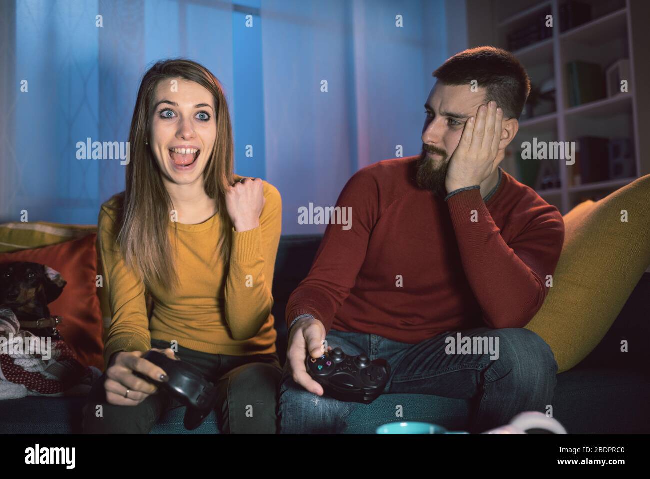 Glückliches Paar, das zu Hause Videospiele spielt, hat gewonnen und feiert mit erhobener Faust Stockfoto