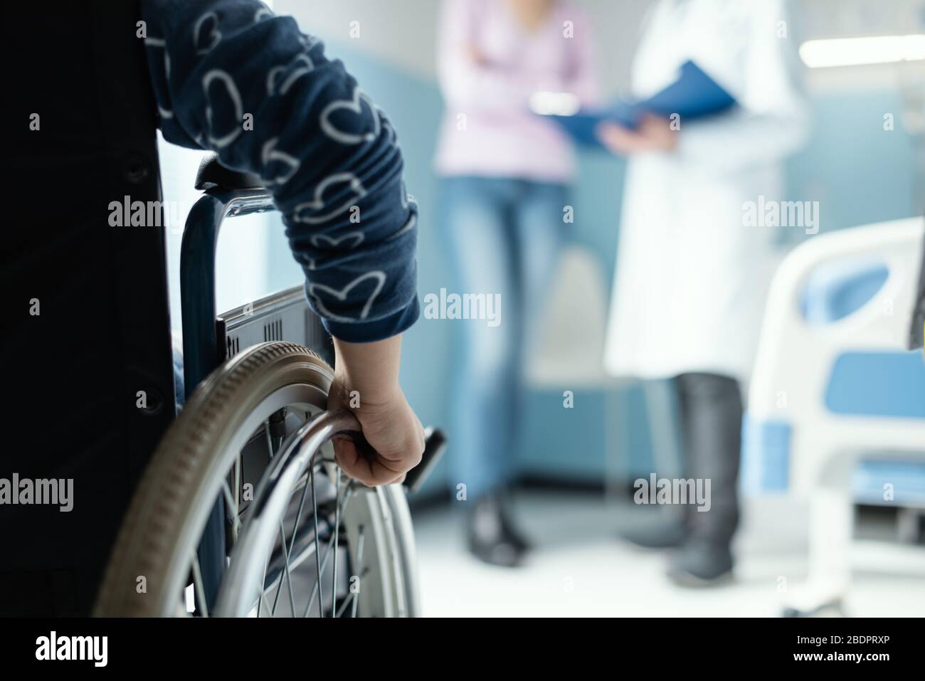 Mädchen im Rollstuhl im Krankenhaus, ihre Mutter und der Arzt diskutieren über ihre Gesundheit Stockfoto