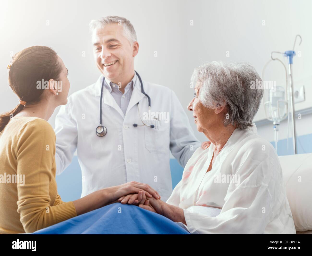 Professioneller lächelnder Arzt, der eine leitende Patientin und ihre Tochter im Krankenhaus, medizinisches Servicekonzept, treffen wird Stockfoto