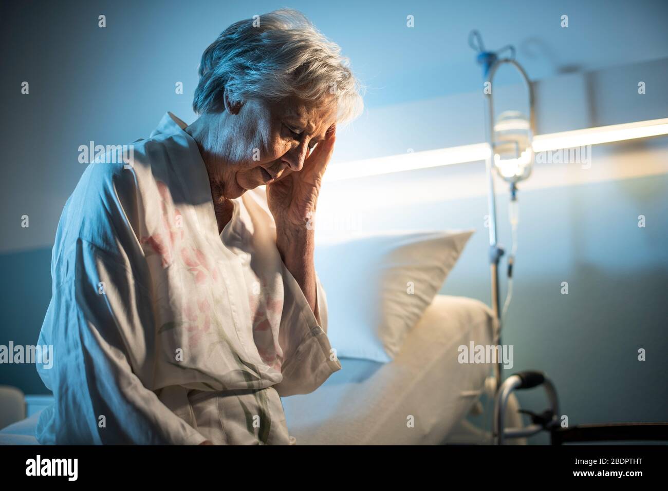 Einsame Oberin, die Kopfschmerzen hat, sitzt sie auf dem Krankenbett und fühlt sich traurig an Stockfoto