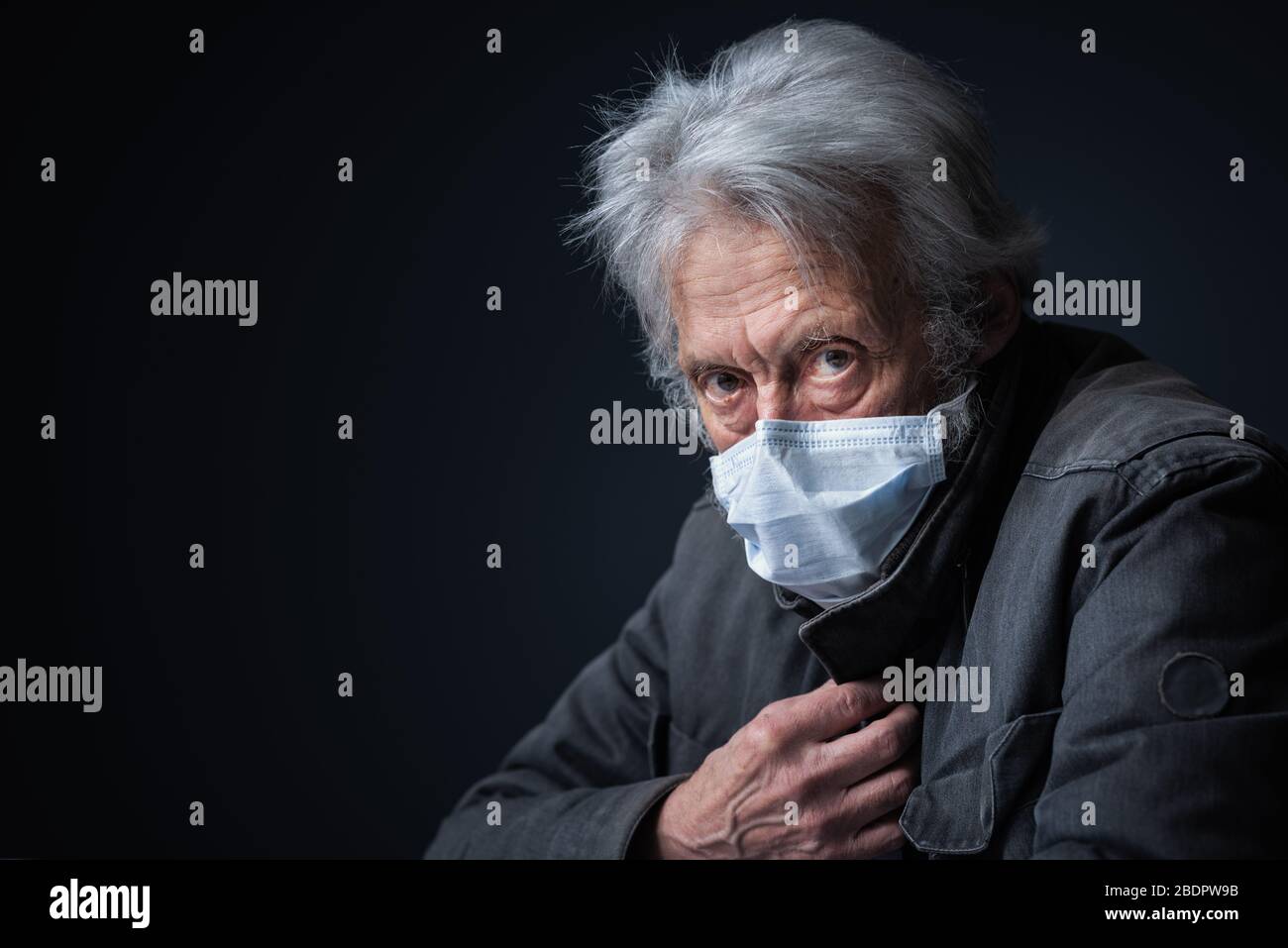 Älterer Mann, der eine Gesichtsschutzmaske trägt und Kamera, Kovid-19-Ausbruch und Oberpflegekonzept betrachtet Stockfoto