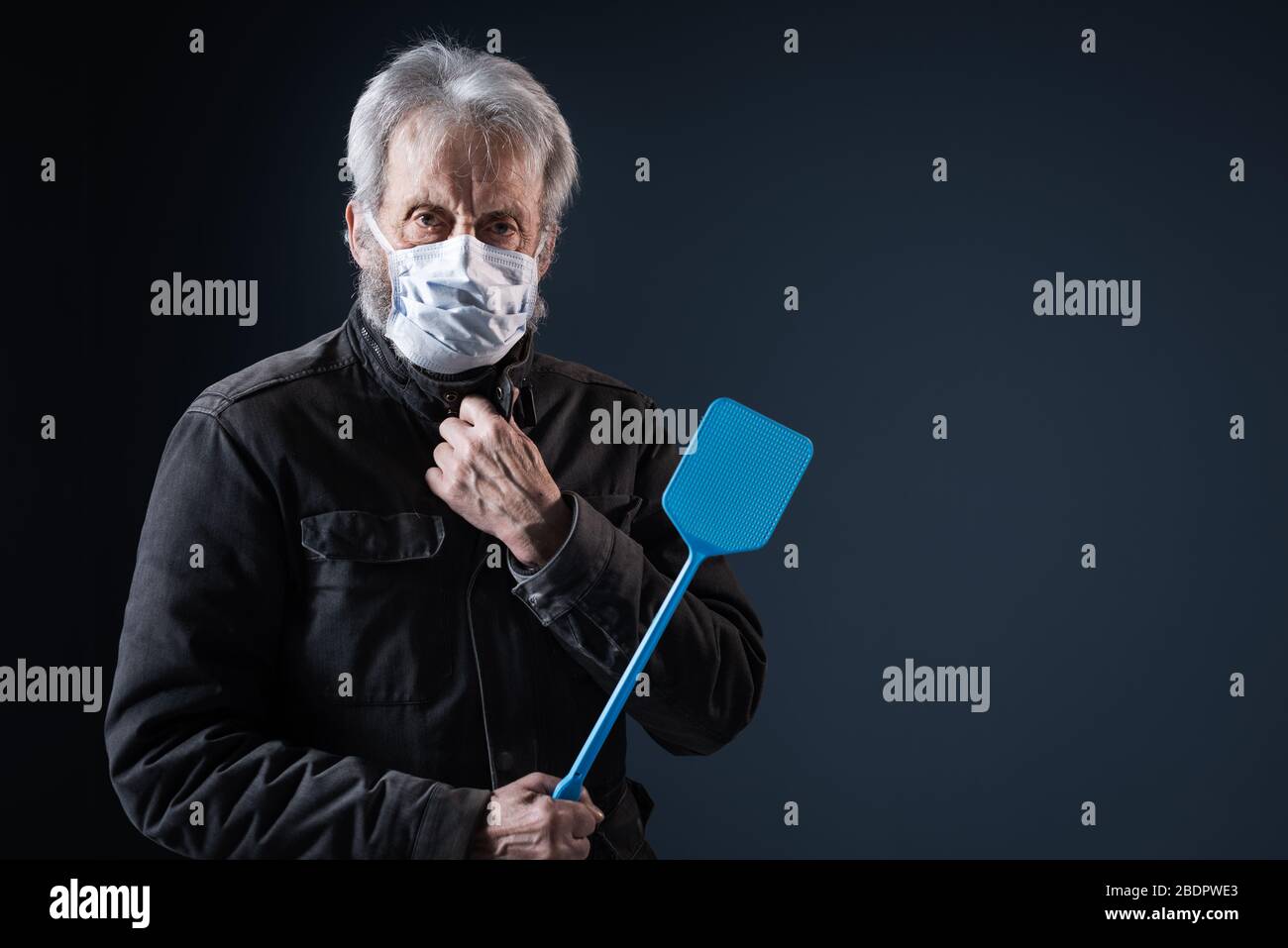 Selbstbewusster Senior schützt sich vor dem Virus Covid-19, er trägt eine Gesichtsmaske und hält einen Schwatter Stockfoto