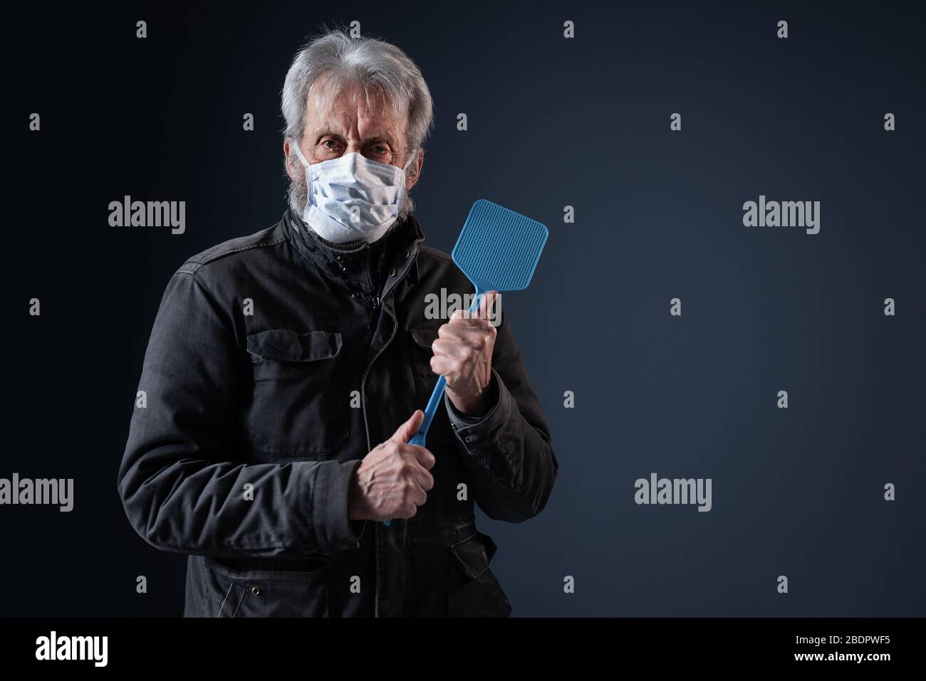 Selbstbewusster Senior schützt sich vor dem Virus Covid-19, er trägt eine Gesichtsmaske und hält einen Schwatter Stockfoto