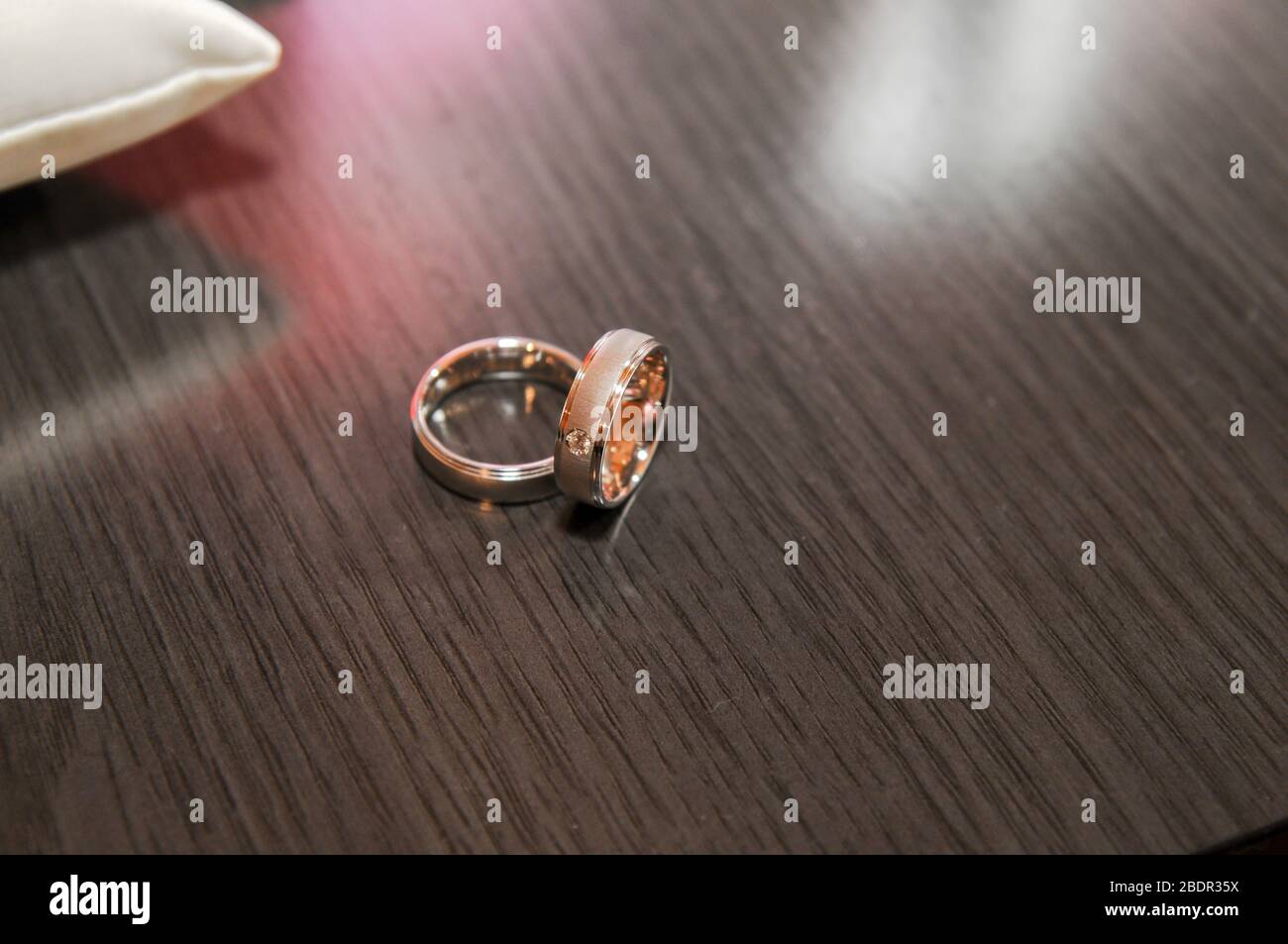 Schöner Ring mit Brillant neben einem anderen Ring auf einer Holzfläche Stockfoto