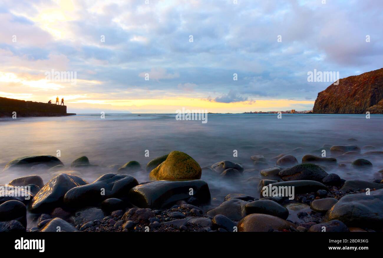 Der Atlantische Ozean und Steine am Strand bei Sonnenuntergang auf der Insel Tenera, den Kanaren - lange Exposition Stockfoto