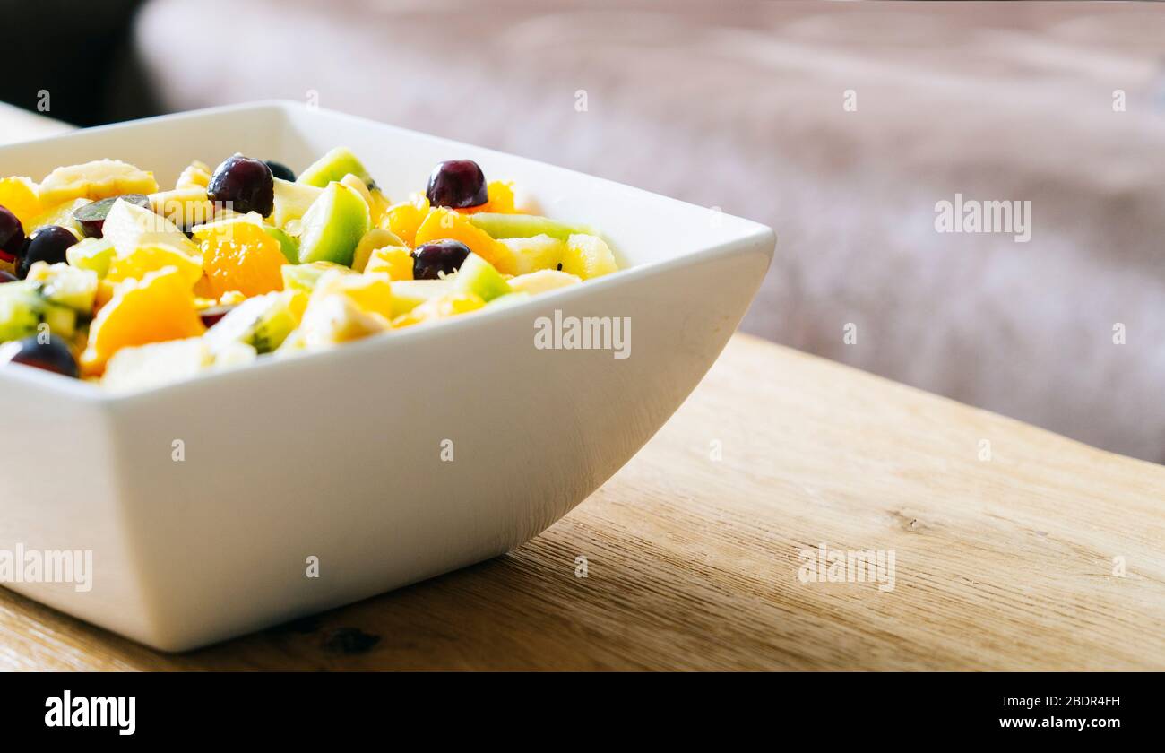 Ein Obstsalat in einer weißen Schüssel auf einem Holztisch Stockfoto