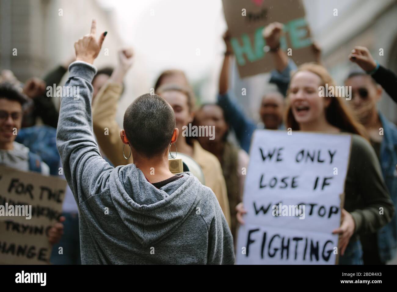 Weibliche Aktivistin schreit in einem protestmarsch auf ein Megafon. Jugendliche protestieren mit Plakaten und Megafon. Stockfoto