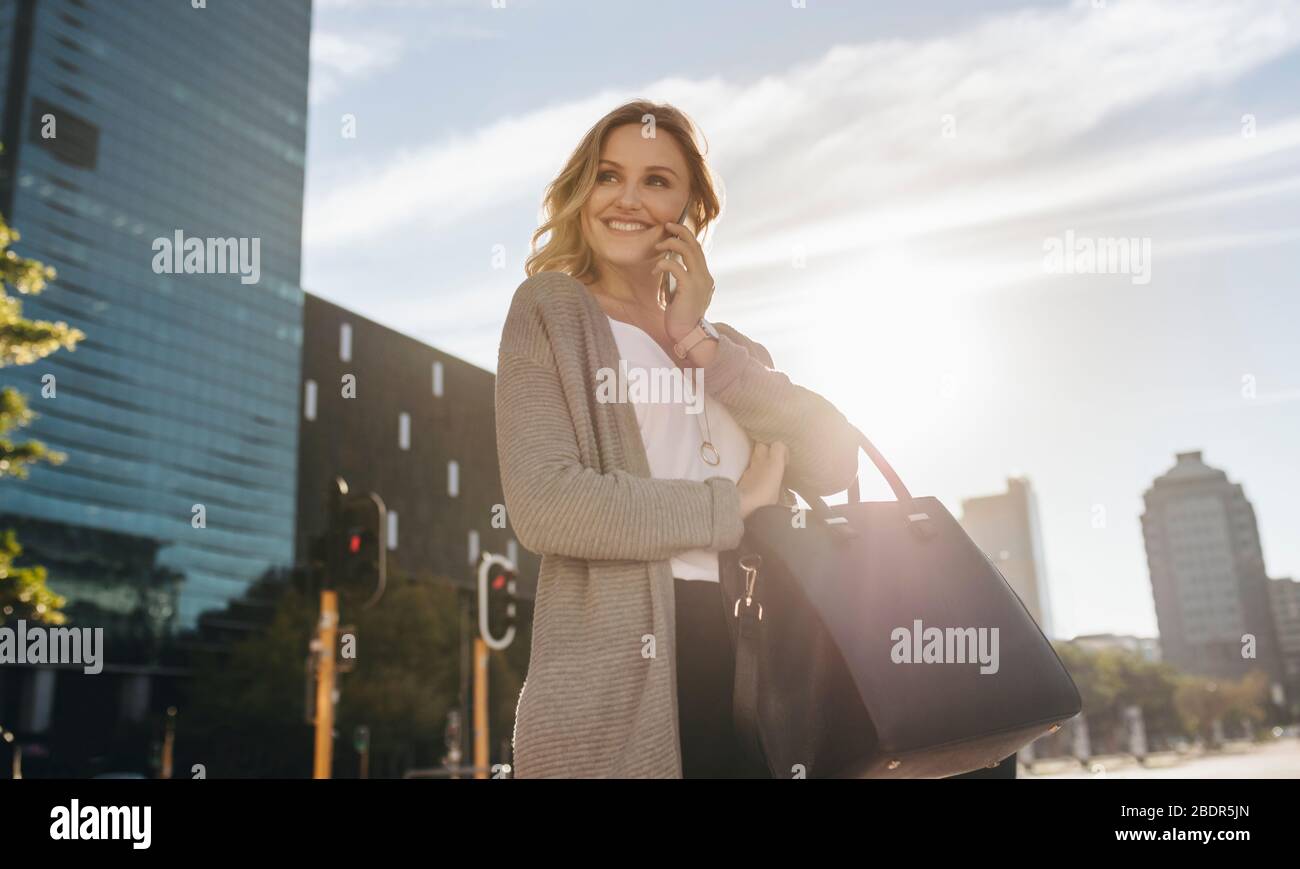 Geschäftsfrau, die draußen läuft und mit dem Handy spricht. Geschäftsfrau, die auf der Straße telefoniert Stockfoto