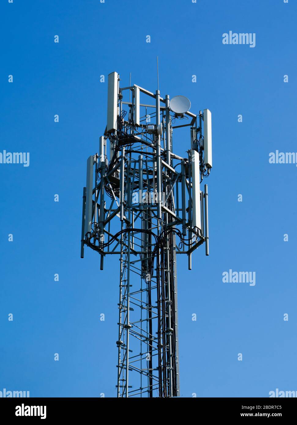 Spitze eines Mobilfunkmasts vor einem schlichten blauen Himmel Hintergrund in Perry Green, Much Hadham, Hertfordshire. GROSSBRITANNIEN Stockfoto