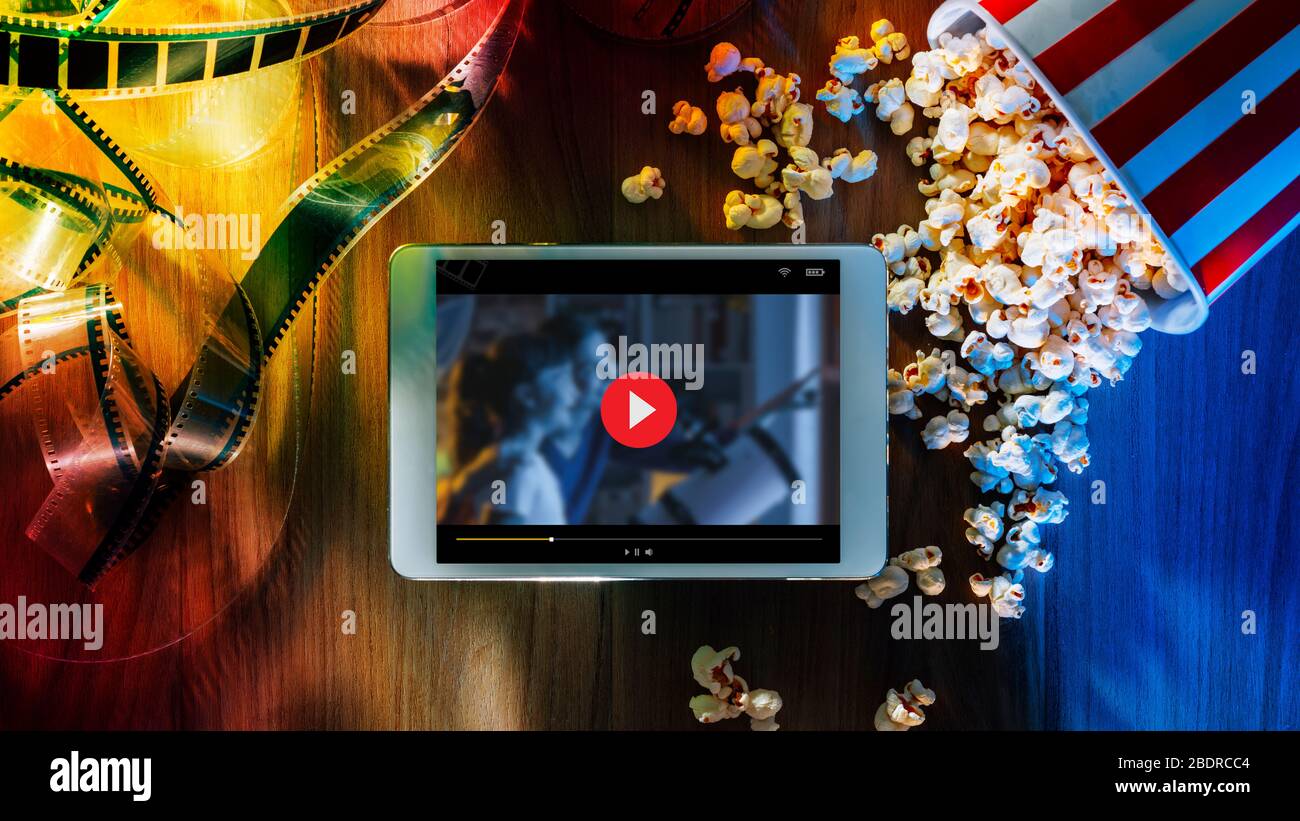 Digitales Touchscreen-Tablet mit Popcorn und Filmstreifen; Online-Streaming-Kino- und Unterhaltungskonzept für Filme Stockfoto