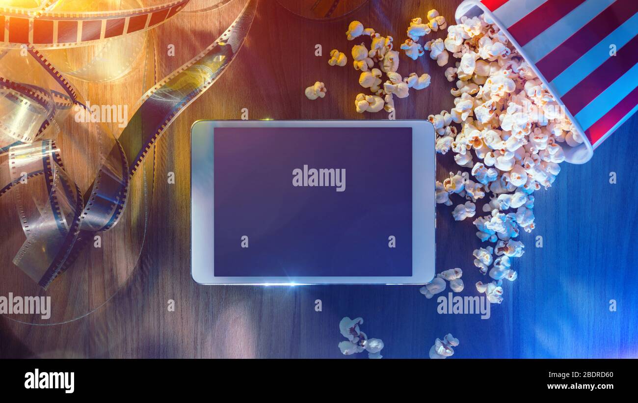 Digitales Touchscreen-Tablet mit Popcorn und Filmstreifen; Online-Streaming-Kino- und Unterhaltungskonzept für Filme Stockfoto