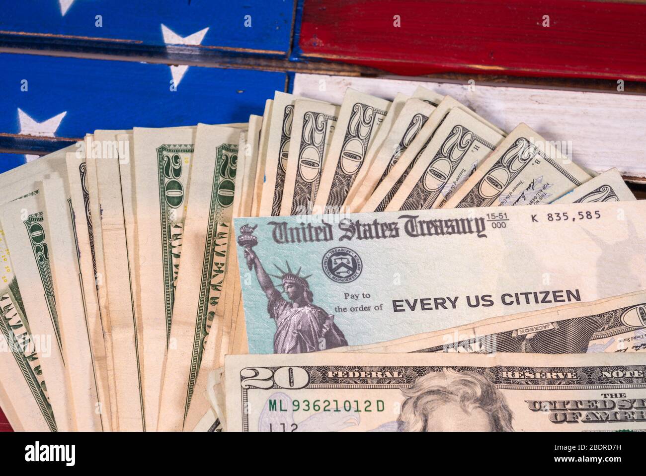 Stapel von 20-Dollar-Schecks mit einem illustrierenden Coronavirus Stimulus Payment Check auf US-Flagge Stockfoto