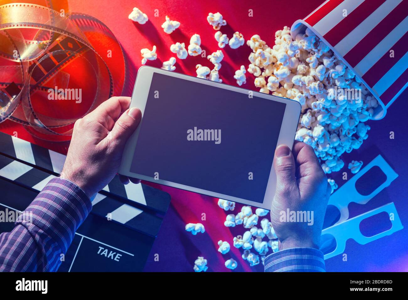 Hände, die ein leeres digitales Tablet, Popcorn, 3D-Brille und Filmstreifen, ein Online-Streaming-Konzept für Kino und Film halten Stockfoto