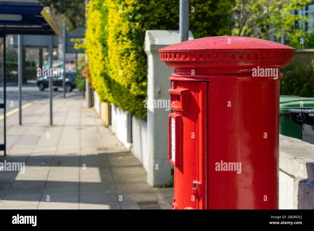 Ein roter königlicher Briefkasten auf einer leeren Straße Stockfoto