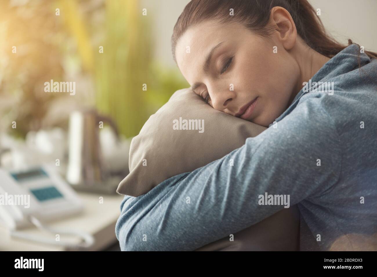 Unglücklich einsame depressive Frau zu Hause sitzt sie auf der Couch und umarmt ein weiches Kissen, ein Depressionskonzept Stockfoto