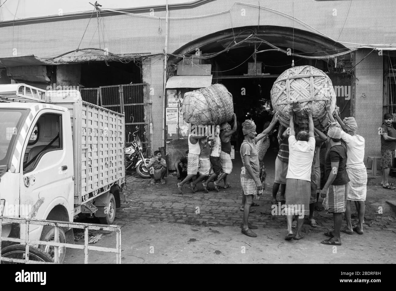 Arbeiter, die eine schwere Ladung Waren in Koley Market, Kalkutta, Indien, aufnehmen. Stockfoto