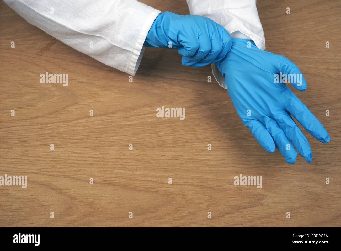 Ärztin mit blauen medizinischen Handschuhen. Studio Foto auf einem hölzernen Hintergrund. Stockfoto