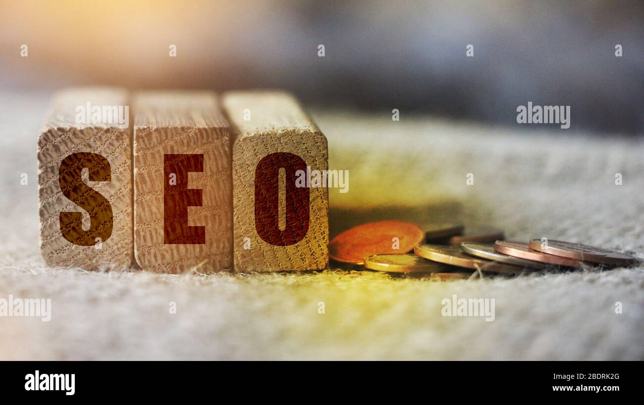 Cubes mit dem Akronym SEO für Suchmaschinen-Optimierung mit Münzen neben. Internet Marketing Konzept Stockfoto